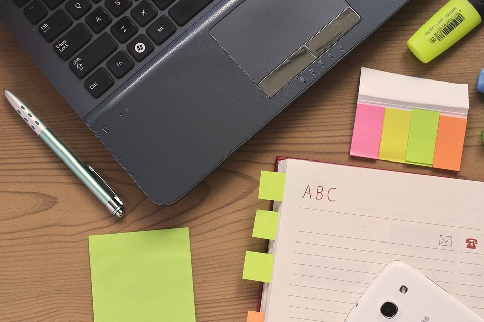 Mesa de trabajo con un portátil y un cuaderno de notas